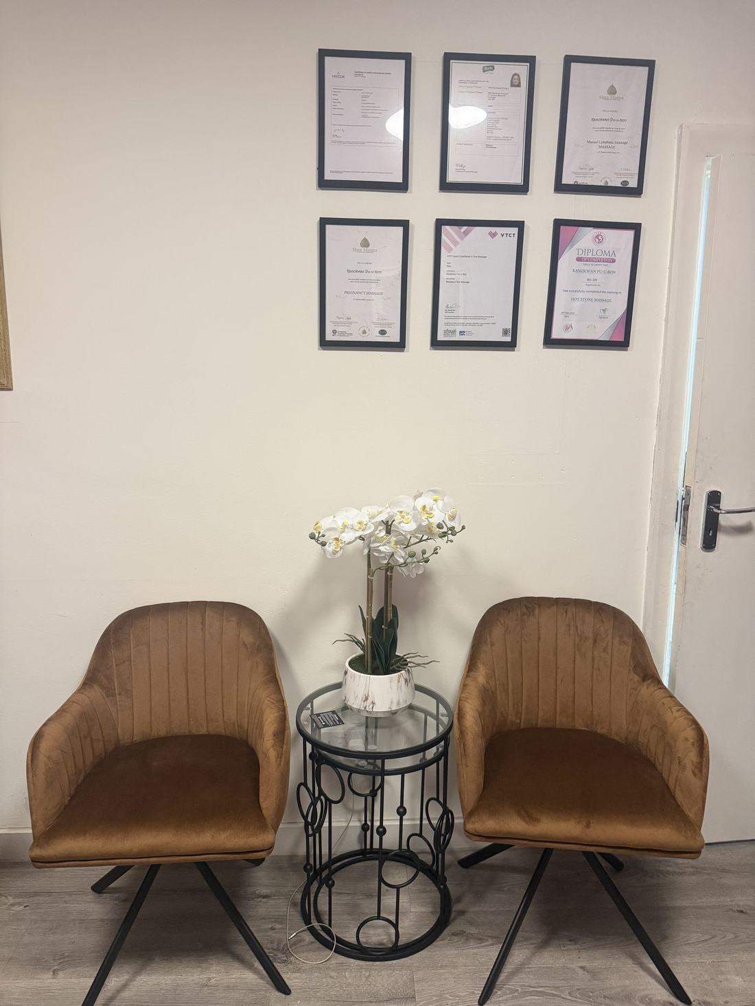 The waiting area: two velvet armchairs, an orchid and framed certificates