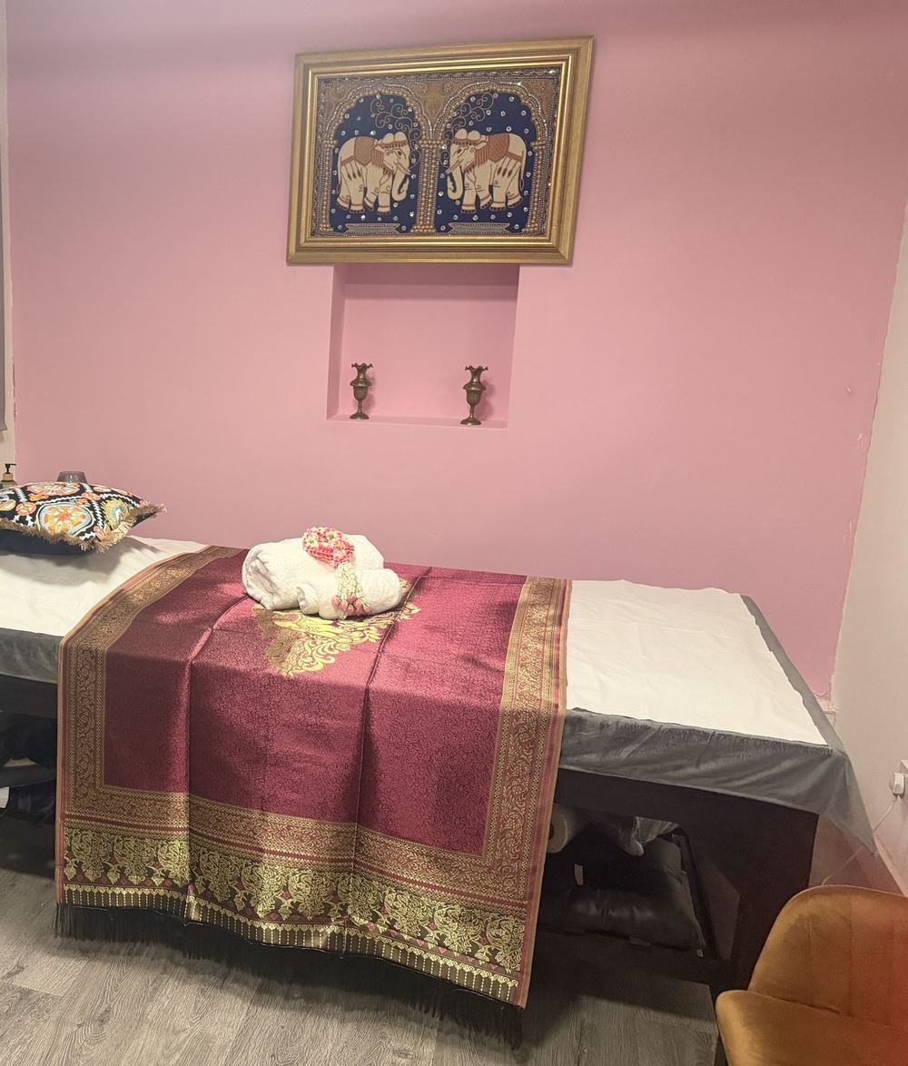 Kanok's treatment room with a silk-dressed massage bed beneath a framed elephant tapestry